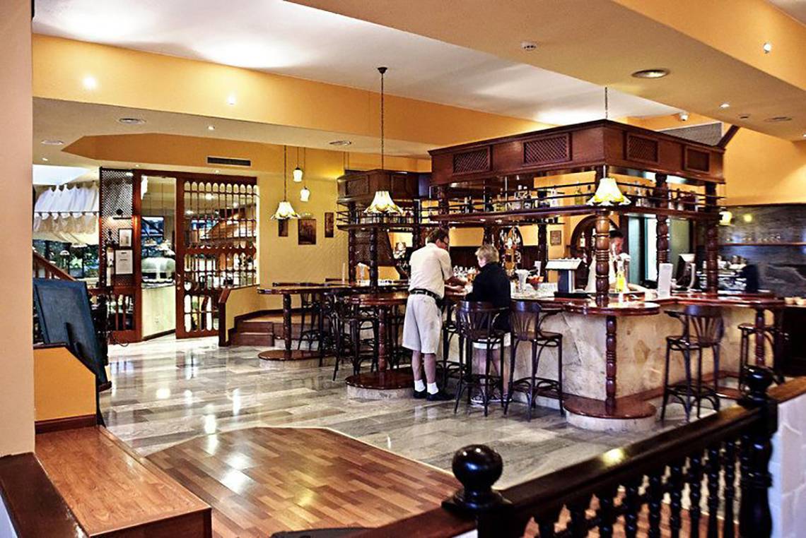Innenansicht der Bar im Hovima Panorama Hotel mit zwei Personen an der Theke.