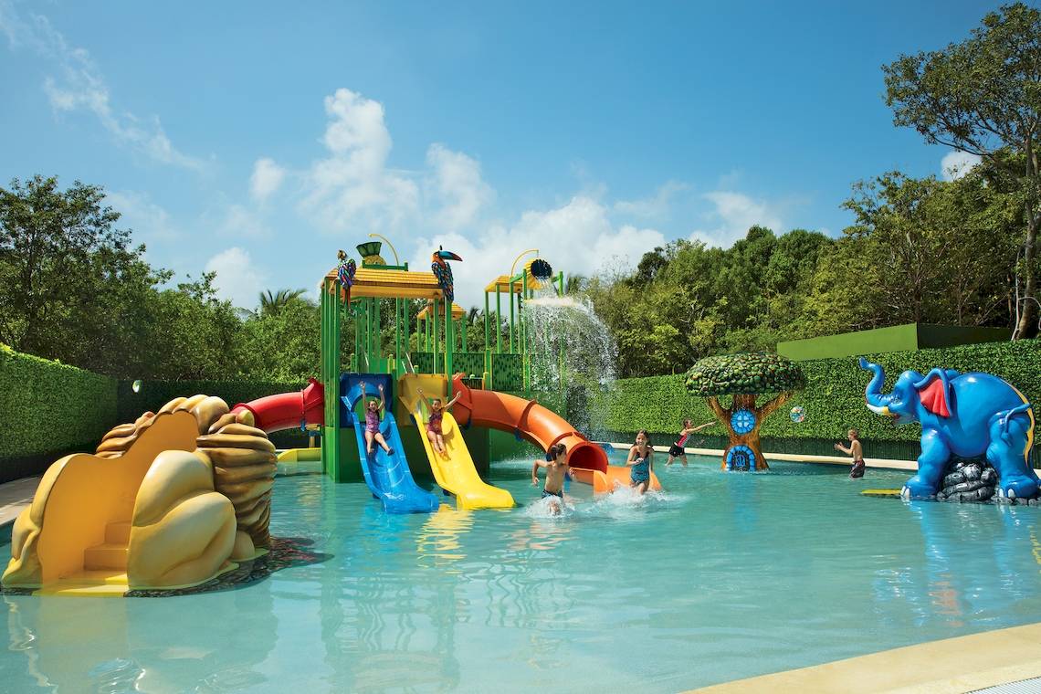 Kinder spielen in einem Wasserpark mit bunten Rutschen und Wasserspielen.