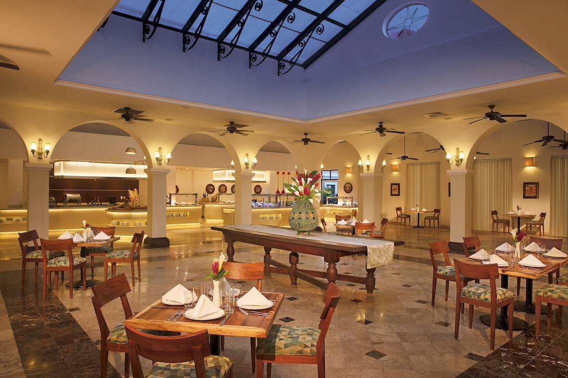 Innenbereich des Restaurants im Dreams Tulum Resort & Spa mit geometrischen Mustern, Holztischen und hängenden Ventilatoren.
