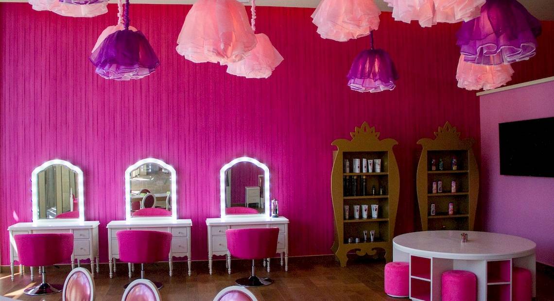 Friseursalon im Barcelo Maya Grand Resort mit pinken Wänden, Spiegeln, Stühlen und Lampen.