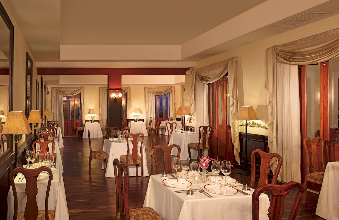 Innenbereich des Restaurants im Dreams Tulum Resort & Spa mit gedeckten Tischen und Stühlen.