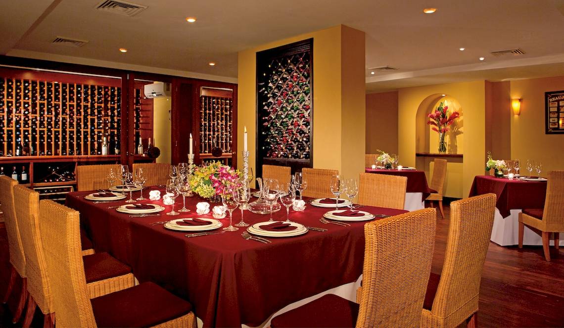 Weinkeller des Dreams Tulum Resort & Spa mit gedecktem Tisch und roten Tischdecken.