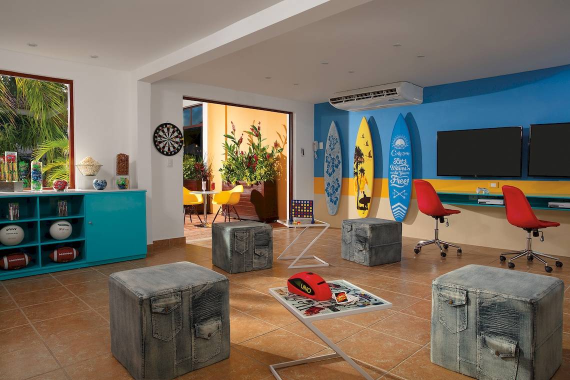 Spielzimmer im Dreams Tulum Resort & Spa mit blauen und gelben Wänden, bunten Möbeln und Spielsachen.