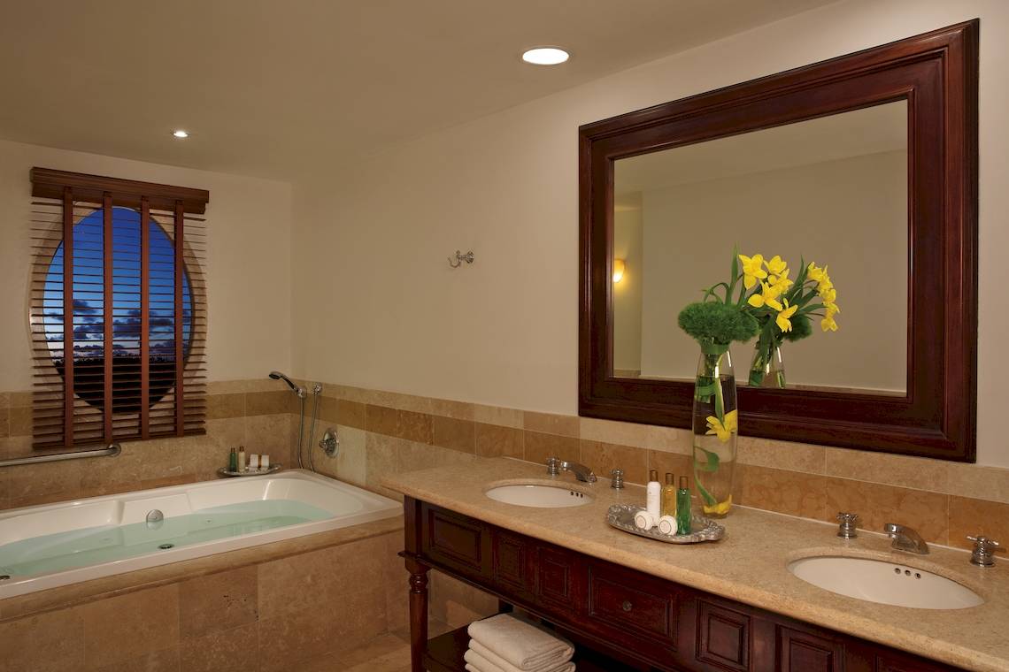 Badezimmer mit Badewanne, Spiegel und Blumenvase im Dreams Tulum Resort & Spa