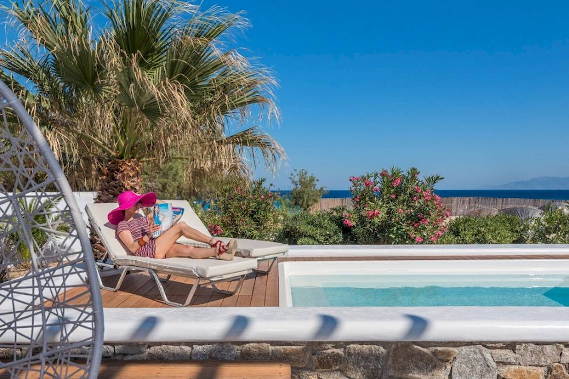 Gäste des Sunrise Mykonos Hotels lesen auf der Terrasse mit Swimmingpool.
