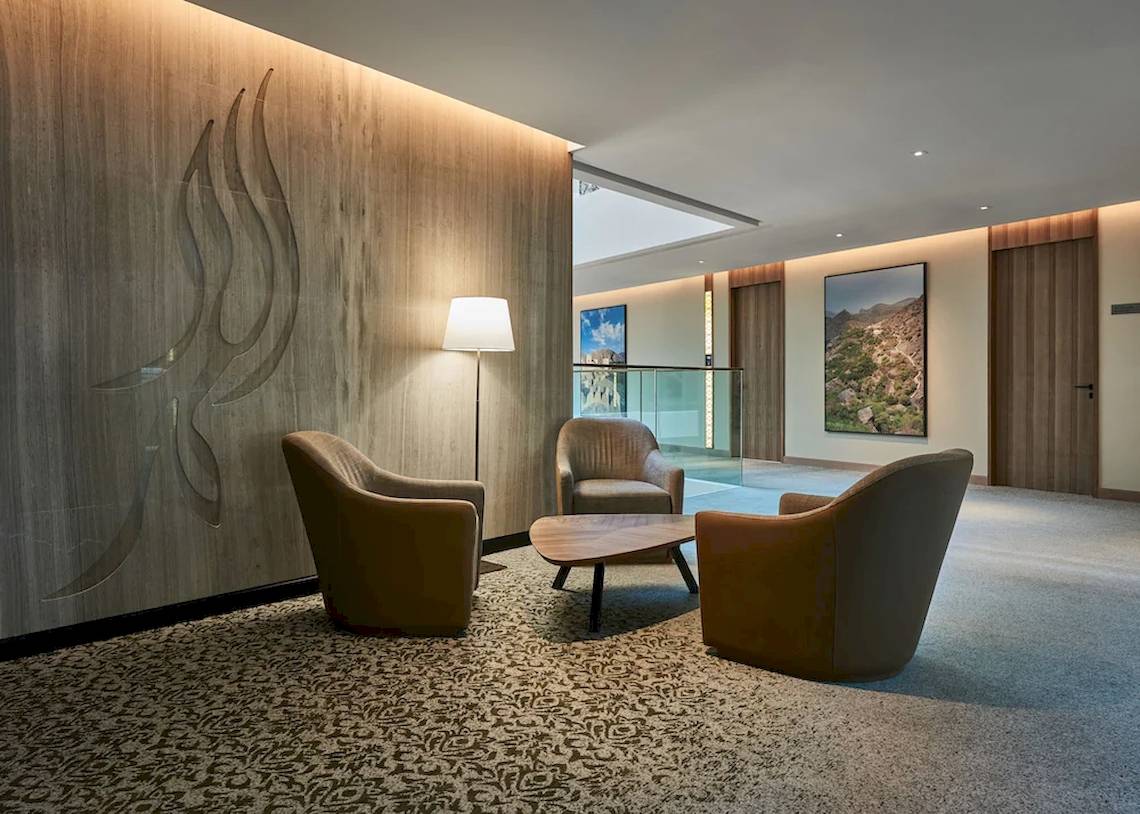Lobby-Lounge-Bereich im Mysk Al Mouj Hotel mit Möbeln, Lampen und Kunstwerken.