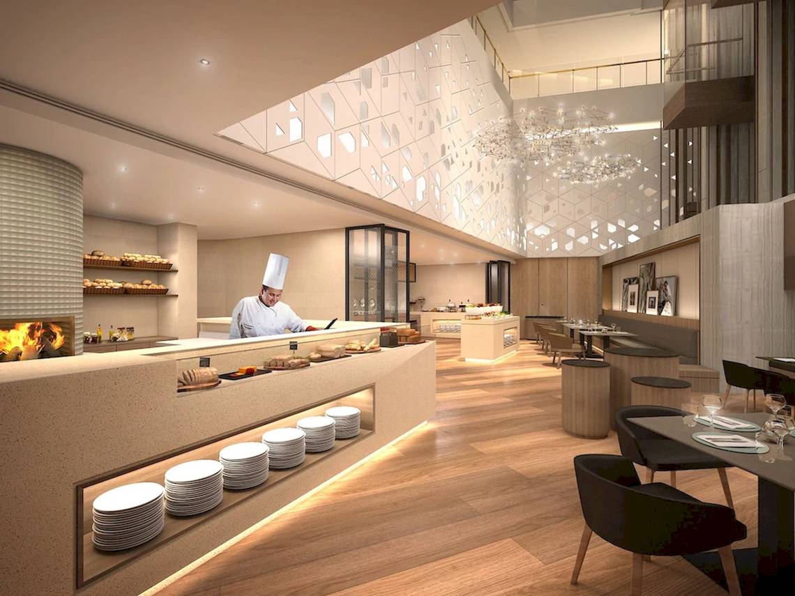 Innenansicht des Mysk Al Mouj Hotels mit einem Koch, der Speisen auf einem Buffet zubereitet.