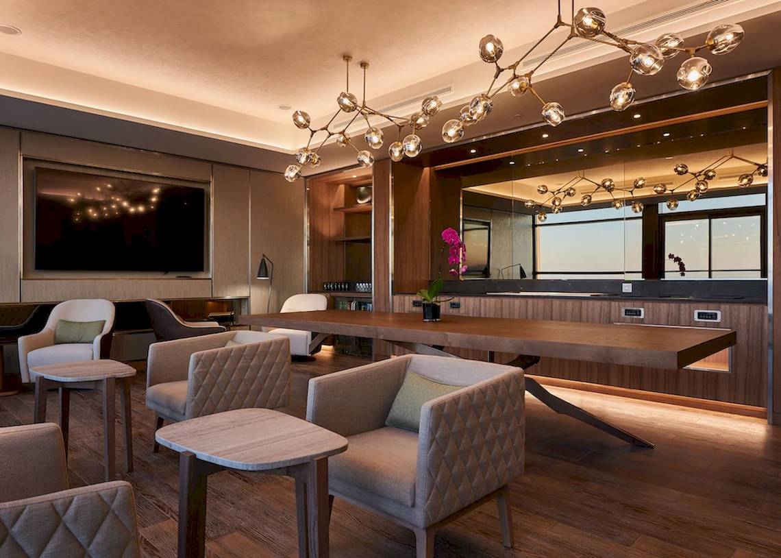 Loungebereich im Mysk Al Mouj Hotel mit Holzmöbeln und großen Fenstern.