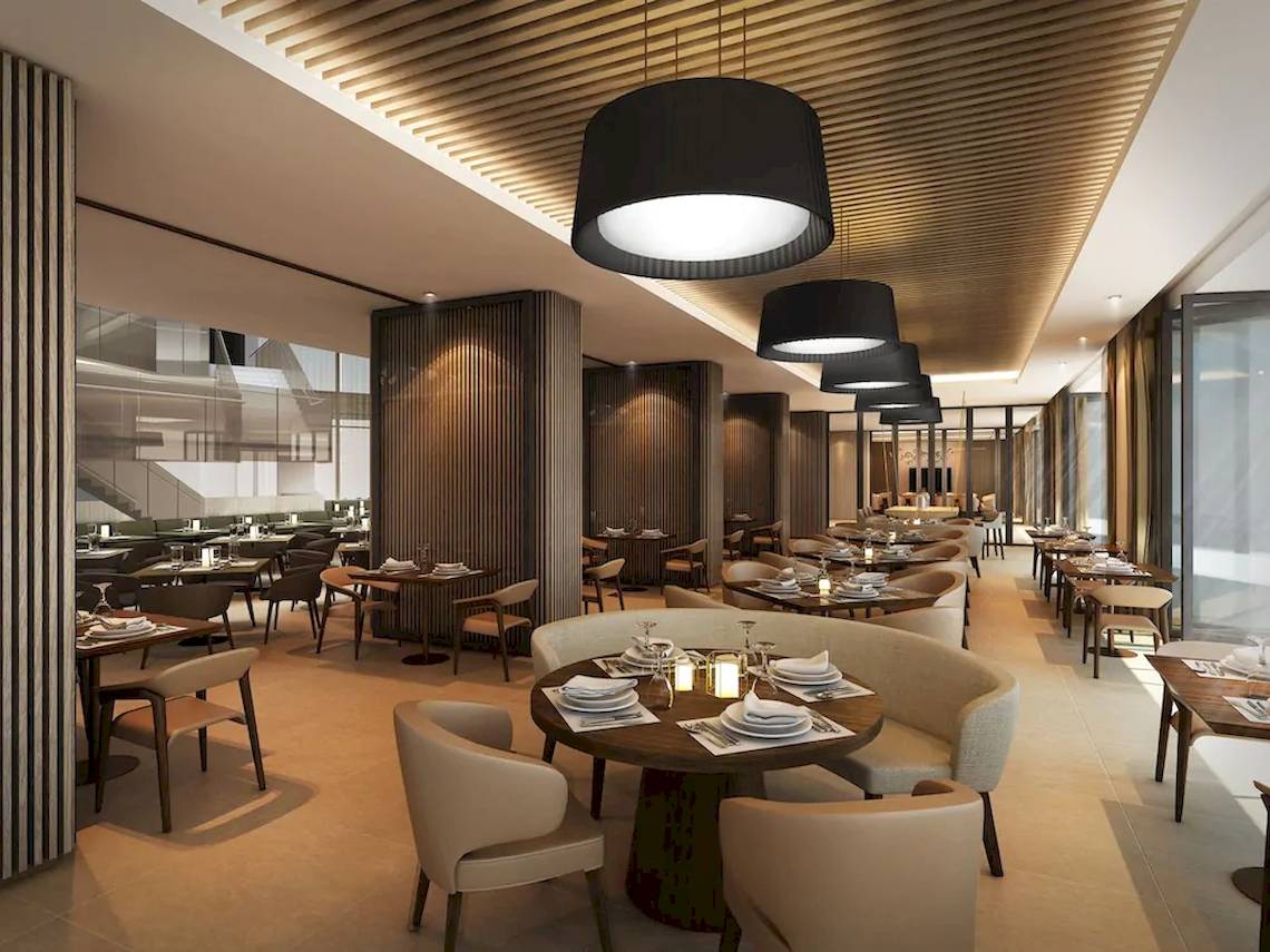 Innenansicht des Restaurants im Mysk Al Mouj Hotel mit modernen Möbeln und warmer Beleuchtung.