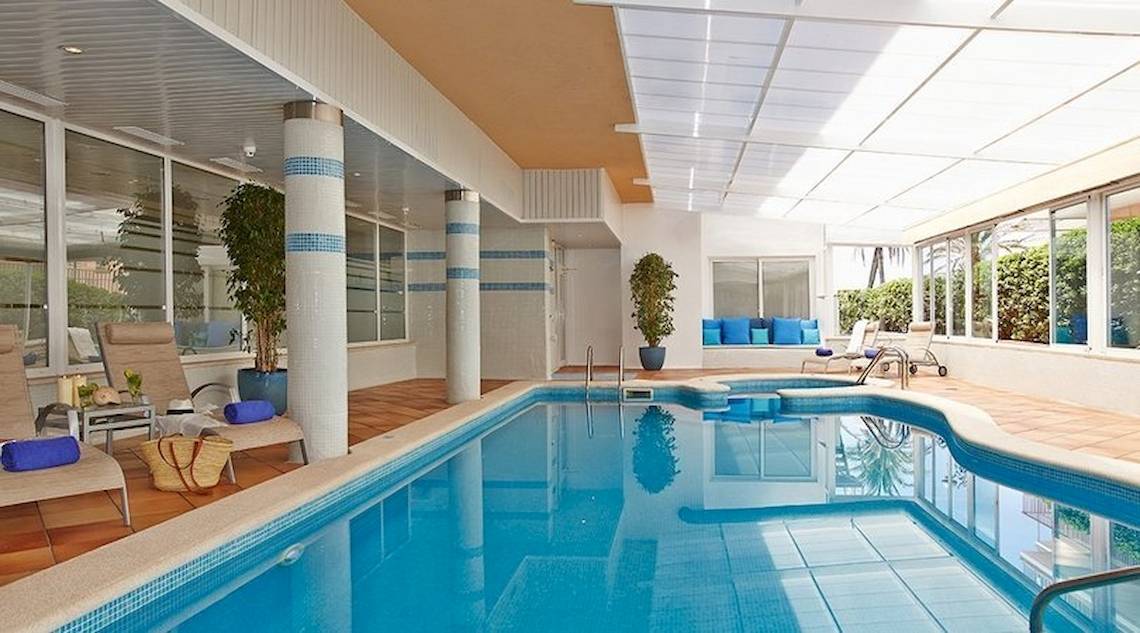 Innenpool im Universal Hotel Neptuno mit Loungebereich und Pflanzen.