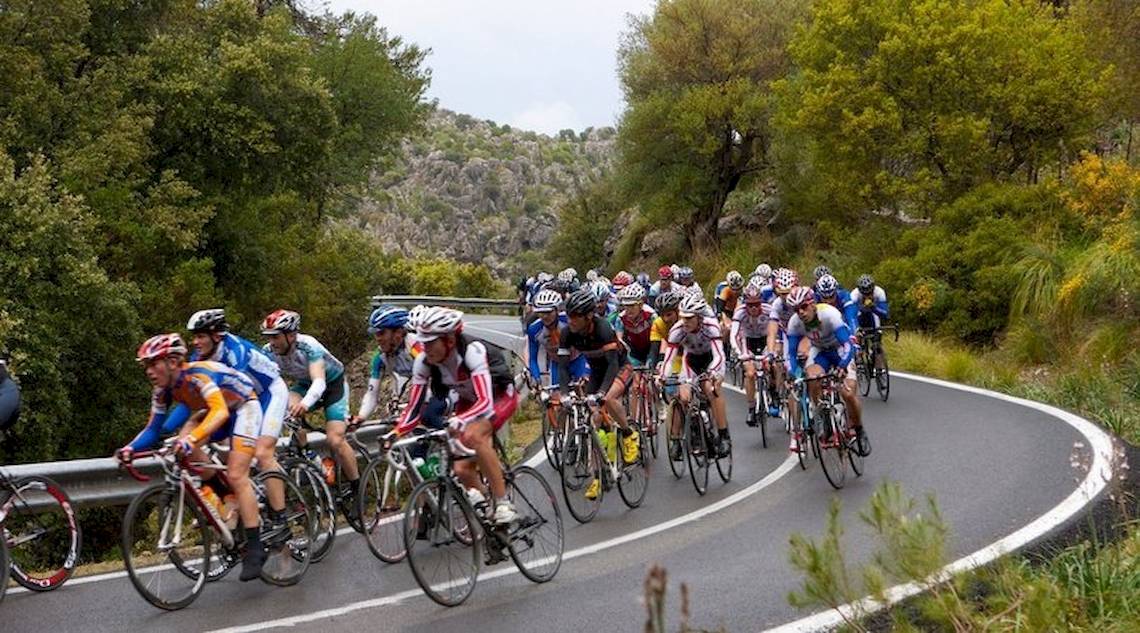 Eine Gruppe von Radfahrern fährt auf einer kurvigen Straße.