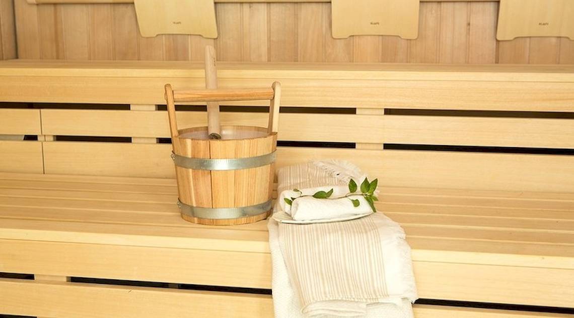 Holzsauna mit einem Holzeimer und Handtüchern auf der Bank.