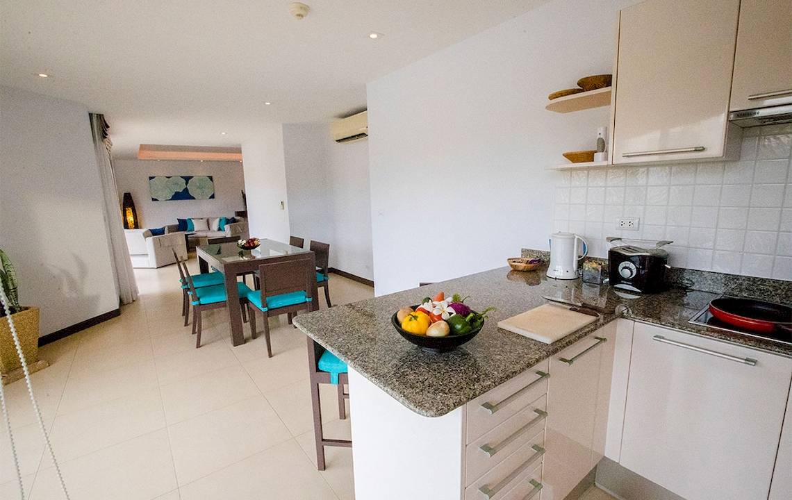 Innenansicht der Küche im Dewa Phuket Resort & Villas mit Esstisch und Obstschale.
