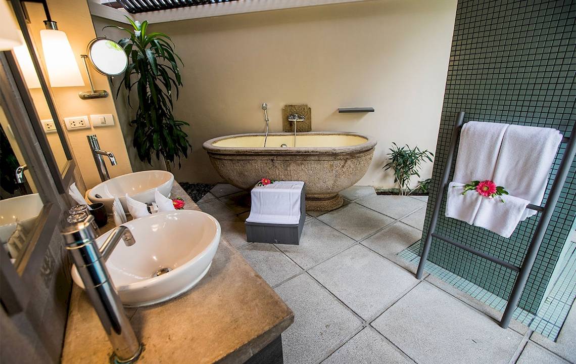 Badezimmer im Dewa Phuket Resort & Villas mit freistehender Badewanne, Waschbecken und Handtüchern.