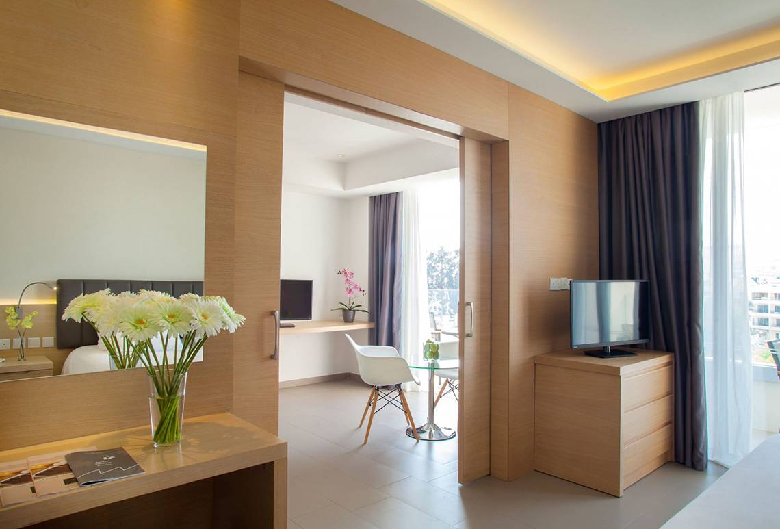 Zimmer im Royal Apollonia Strandhotel mit moderner Einrichtung und Blick auf die Stadt.