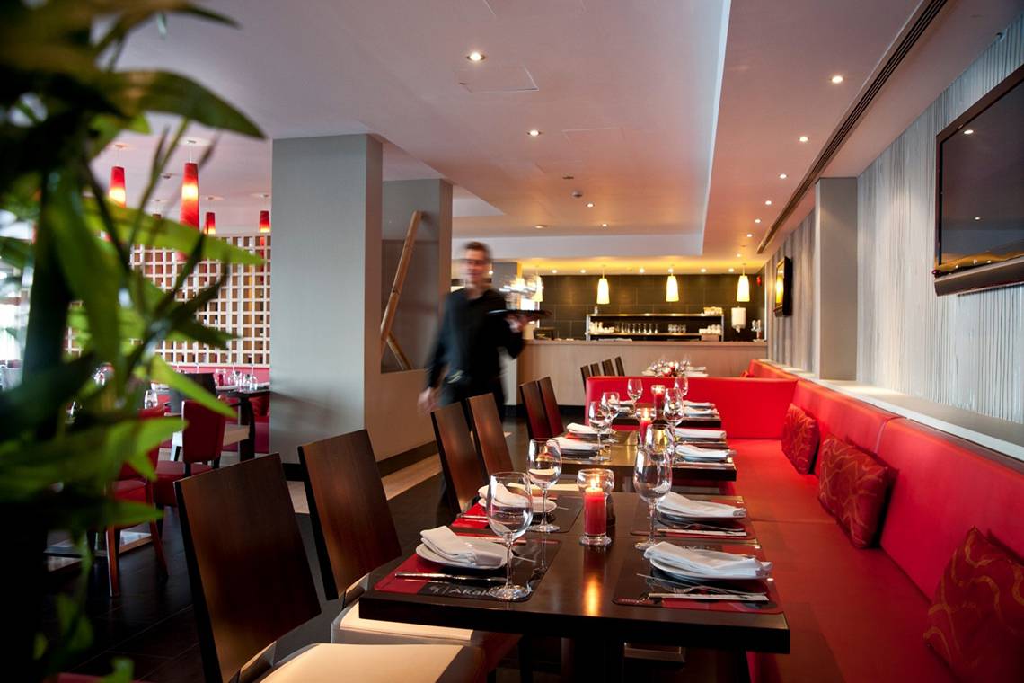 Innenansicht des Restaurants im Royal Apollonia Beach Hotel mit roter Bestuhlung und gedeckten Tischen.