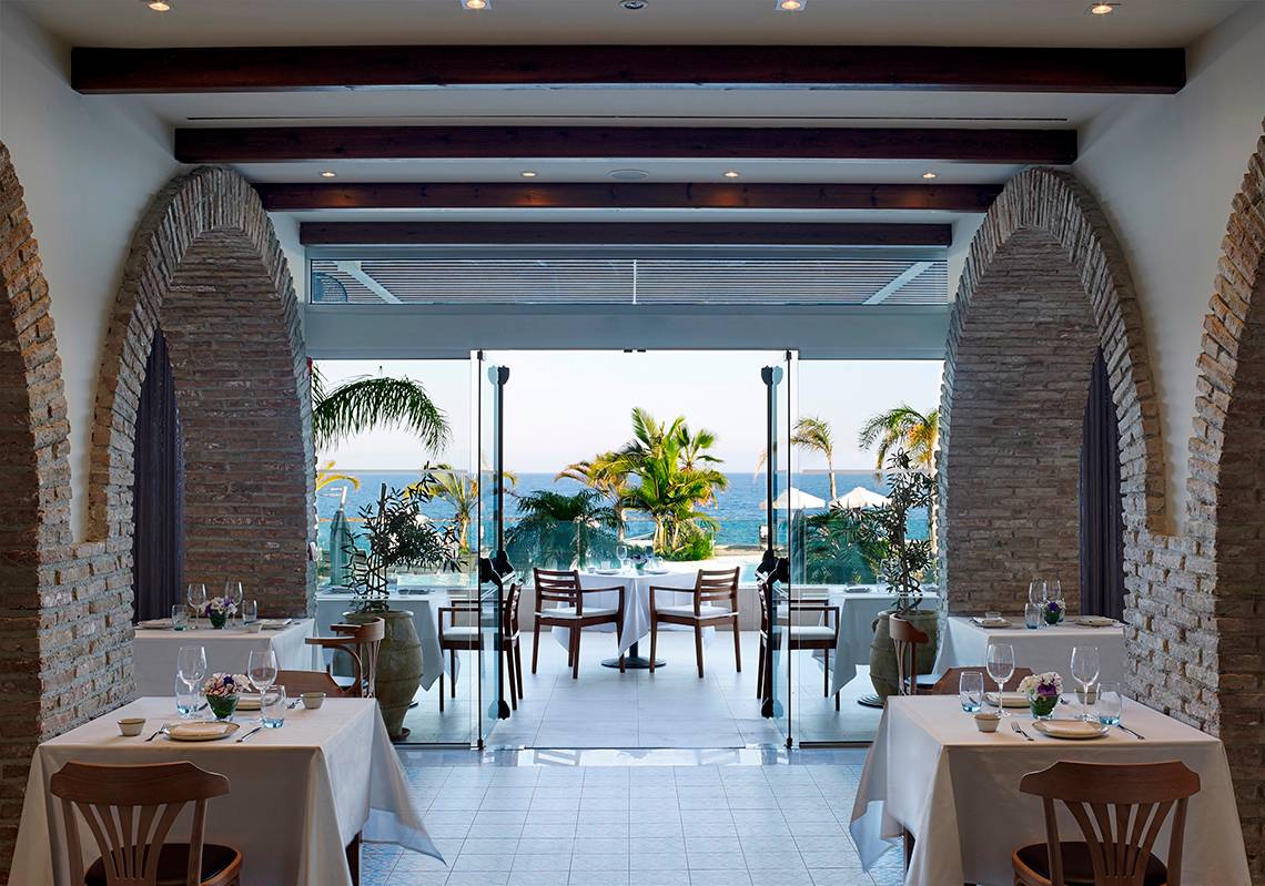 Innenansicht des Restaurants im Royal Apollonia Beach Hotel mit Blick auf das Meer.