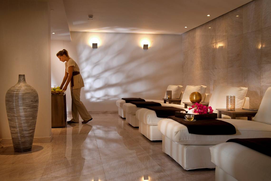 Spa-Lounge im Royal Apollonia Beach Hotel mit weißen Möbeln und hellem Licht.