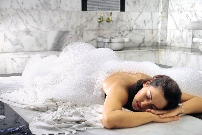 Frau im Sahra Su Holiday Village & Spa Hotel, die in einer Badewanne mit Schaum liegt