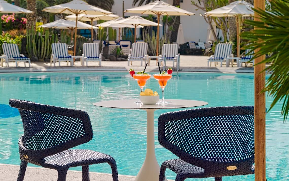 Cocktails am Pool des Seaside Los Jameos Hotels mit Sonnenschirmen und Stühlen im Hintergrund.