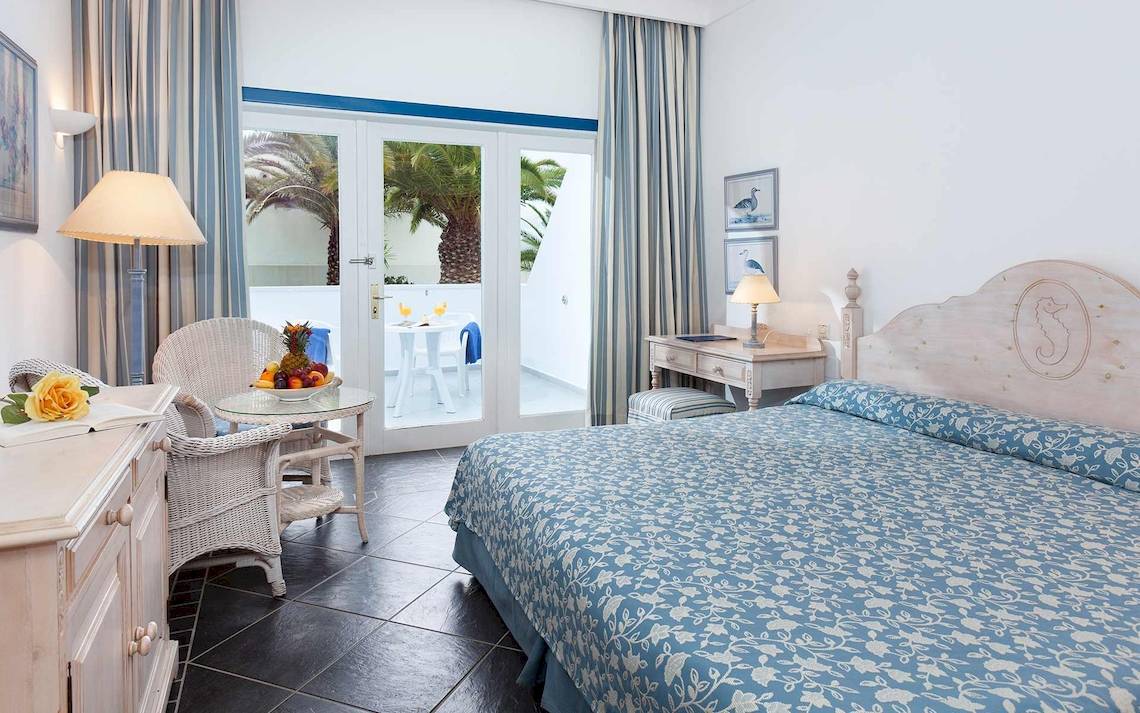 Innenansicht eines Schlafzimmers im Seaside Los Jameos Hotel mit Bett, Balkon, Tisch und Stühle.