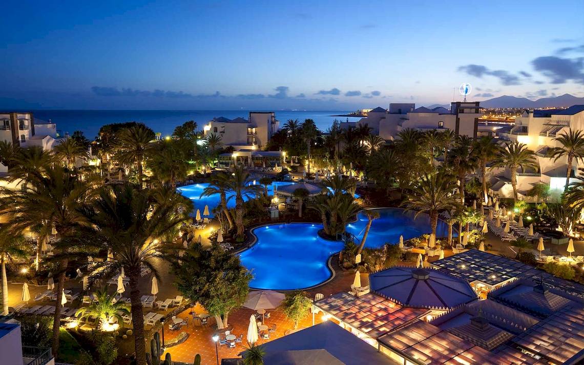 Abendliche Aussicht auf das Seaside Los Jameos Hotel mit Swimmingpool und angelegter Landschaft.