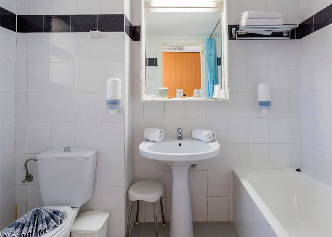 Badezimmer im Olympos Beach Resort mit Badewanne, Toilette, Waschbecken und Spiegel.