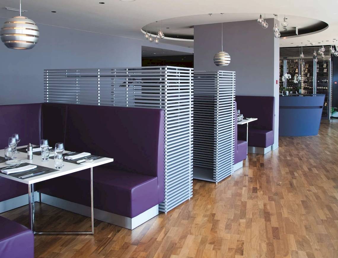 Innenraum des Radisson Blu Resort Split mit violetten Sitzbänken und hölzernem Boden.