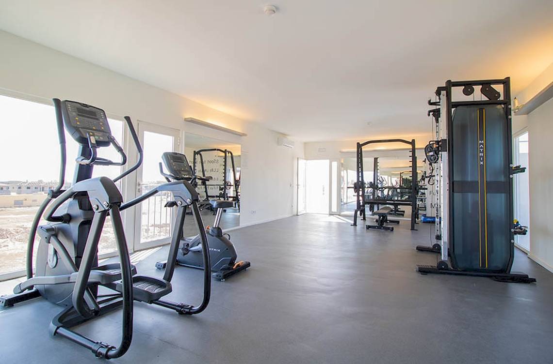Fitnessraum im Hotel Dunas De Sal mit Geräten und Fenstern.
