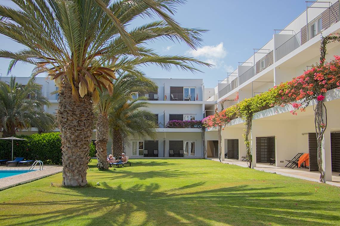 Außenbereich des Dunas De Sal Hotels mit Palme, Pool und Gästebereich.