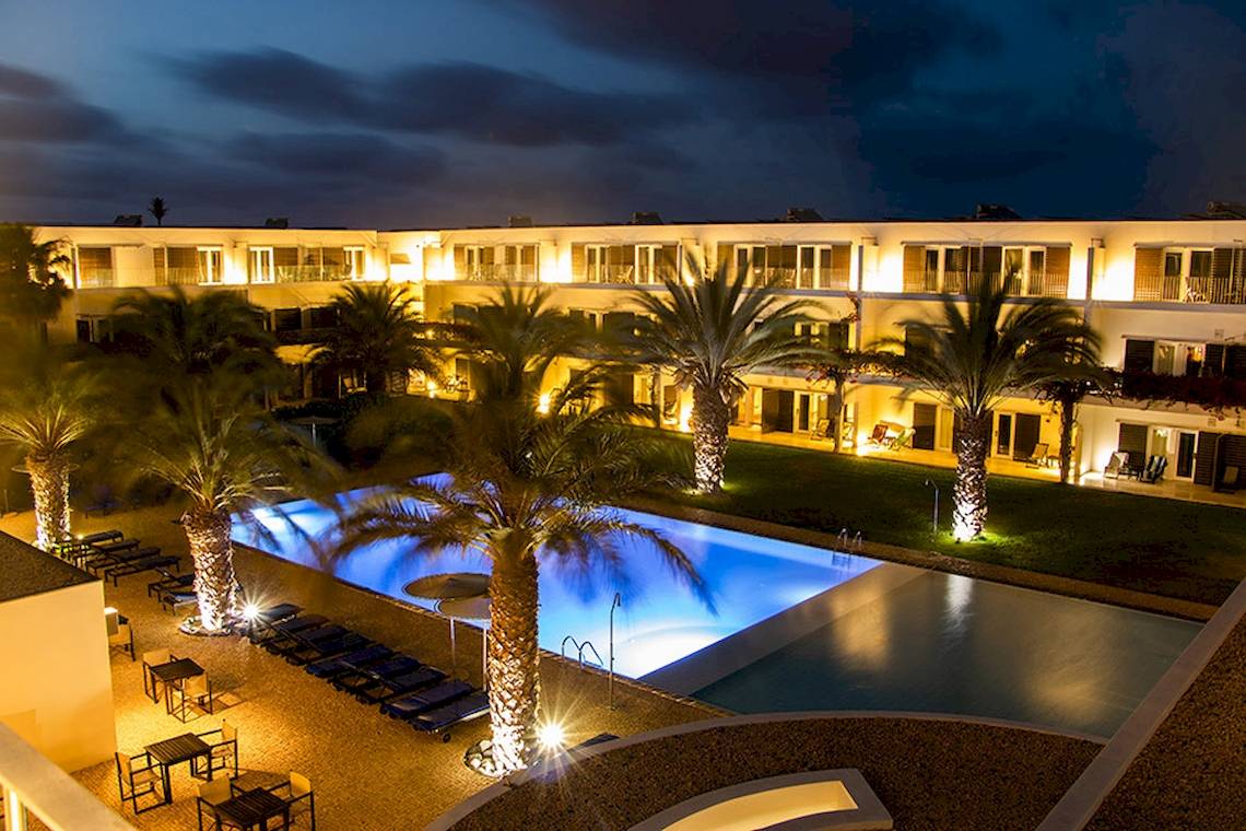 Dunas De Sal Hotel mit beleuchtetem Pool in Nachtansicht.
