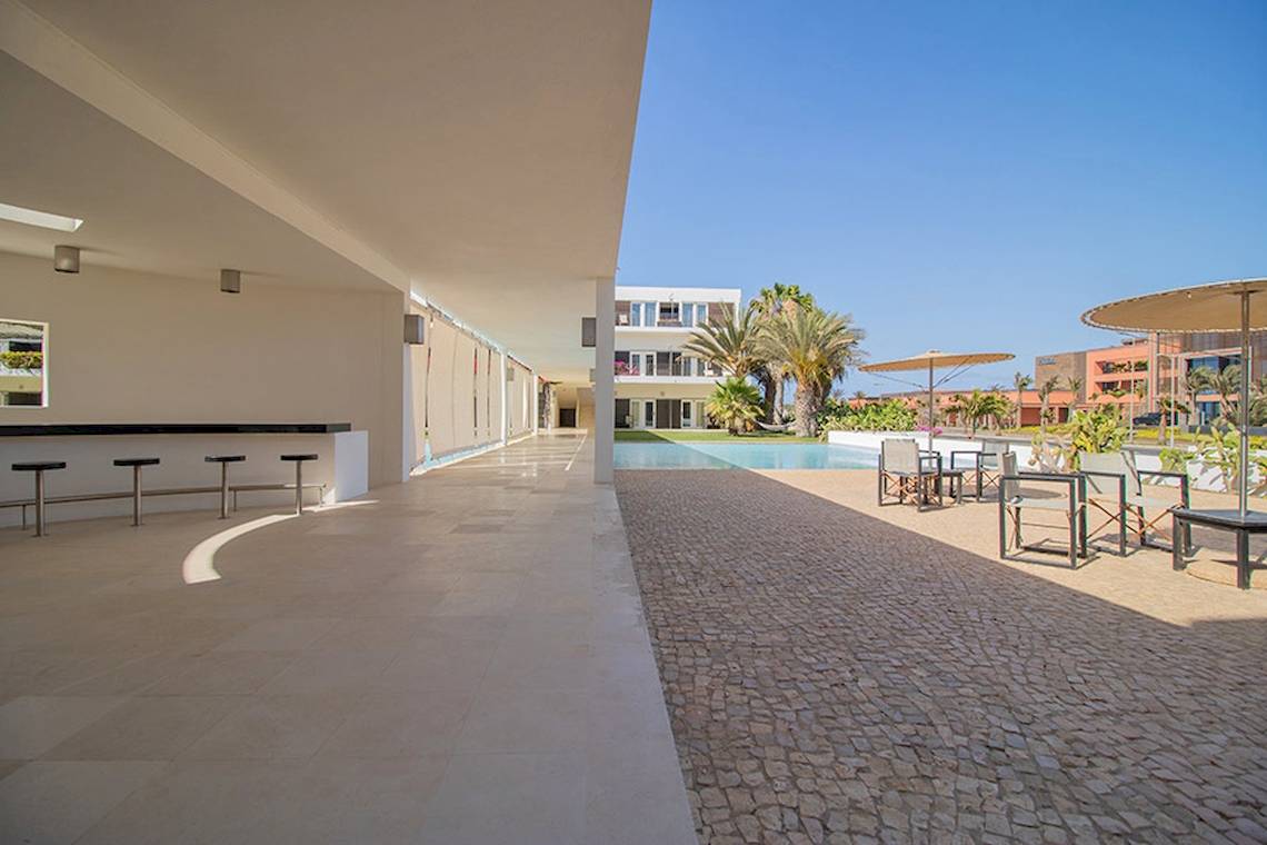 Außenbereich des Dunas De Sal Hotels mit Sitzmöglichkeiten und Pool im Hintergrund.