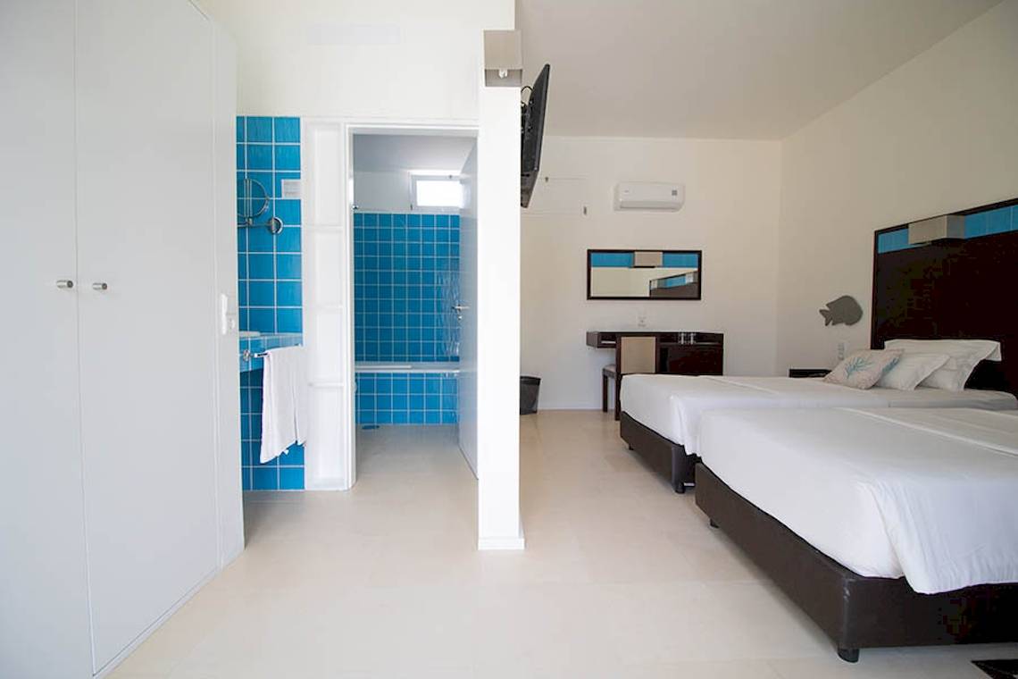 Doppelzimmer im Dunas De Sal Hotel mit zwei Betten und blauen Fliesen.