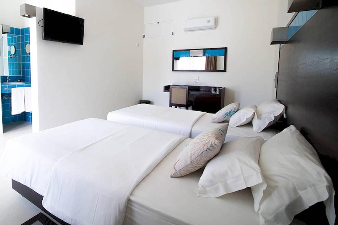 Hotelzimmer im Dunas De Sal mit zwei Betten, blauem Badezimmer und Fernseher.