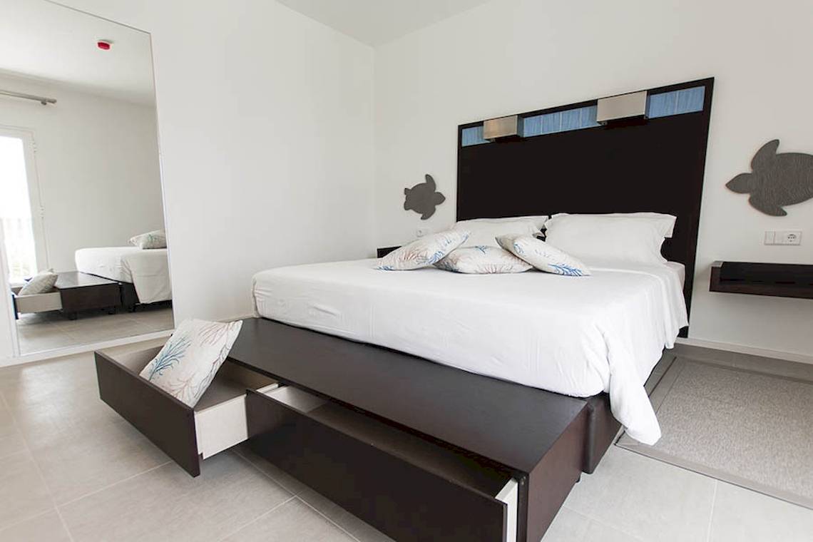 Schlafzimmer im Dunas De Sal Hotel mit weißem Bett und schwarzen Nachttischen.