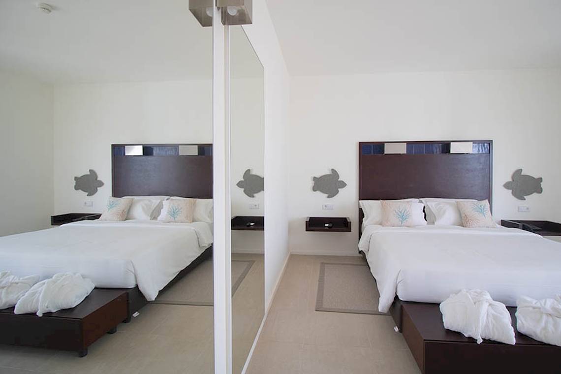 Schlafzimmer im Dunas De Sal Hotel mit zwei Betten und weißen Handtüchern auf Nachttischen.