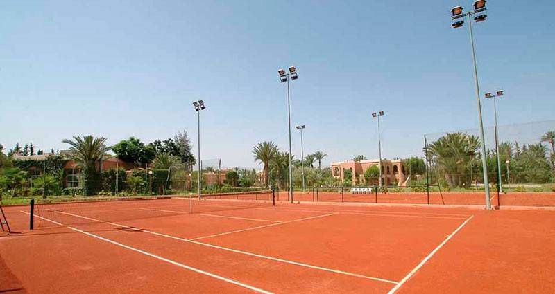 Tennisplatz im Royal Decameron Issil Resort mit roten Spielfeldern und Beleuchtungsmasten.