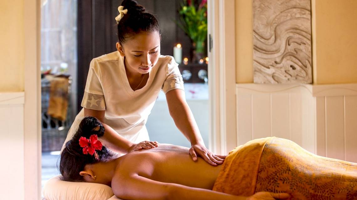 Massage im Paradise Sun Hotel, wo eine Therapeutin eine Rückenmassage an einer Frau durchführt.