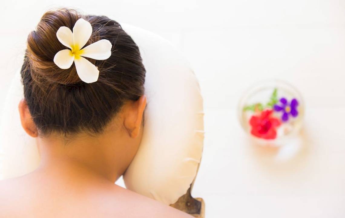 Rückenansicht einer Frau mit Blumenkranz im Hotel