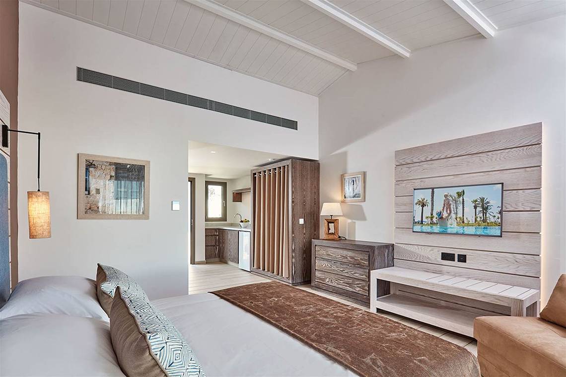 Innenansicht eines Schlafzimmers im Mare Ayia Napa Hotel mit Doppelbett, Dekor und Fernseher.