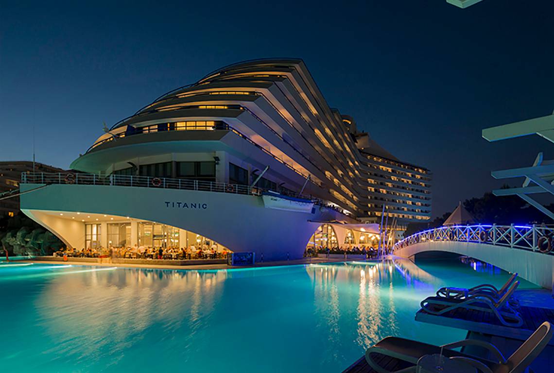 Außenansicht des Titanic Deluxe Lara Hotels mit Pool bei Nacht.