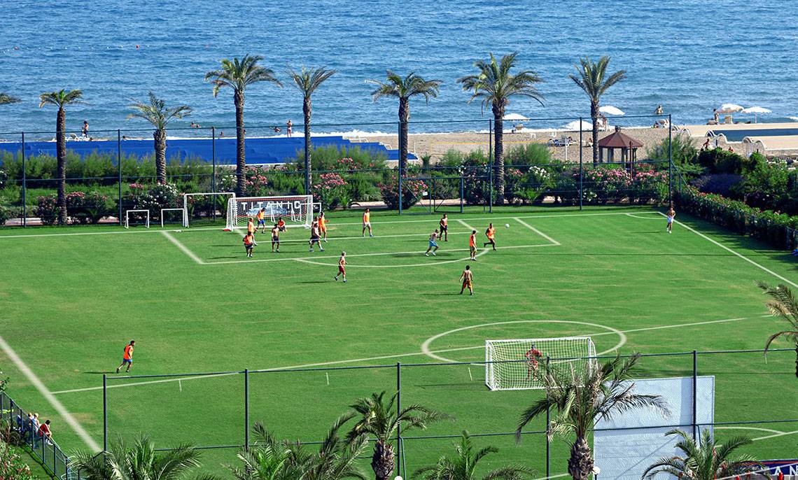 Fußballspiel auf einem Rasenfeld am Strand des Titanic Deluxe Lara Hotels.