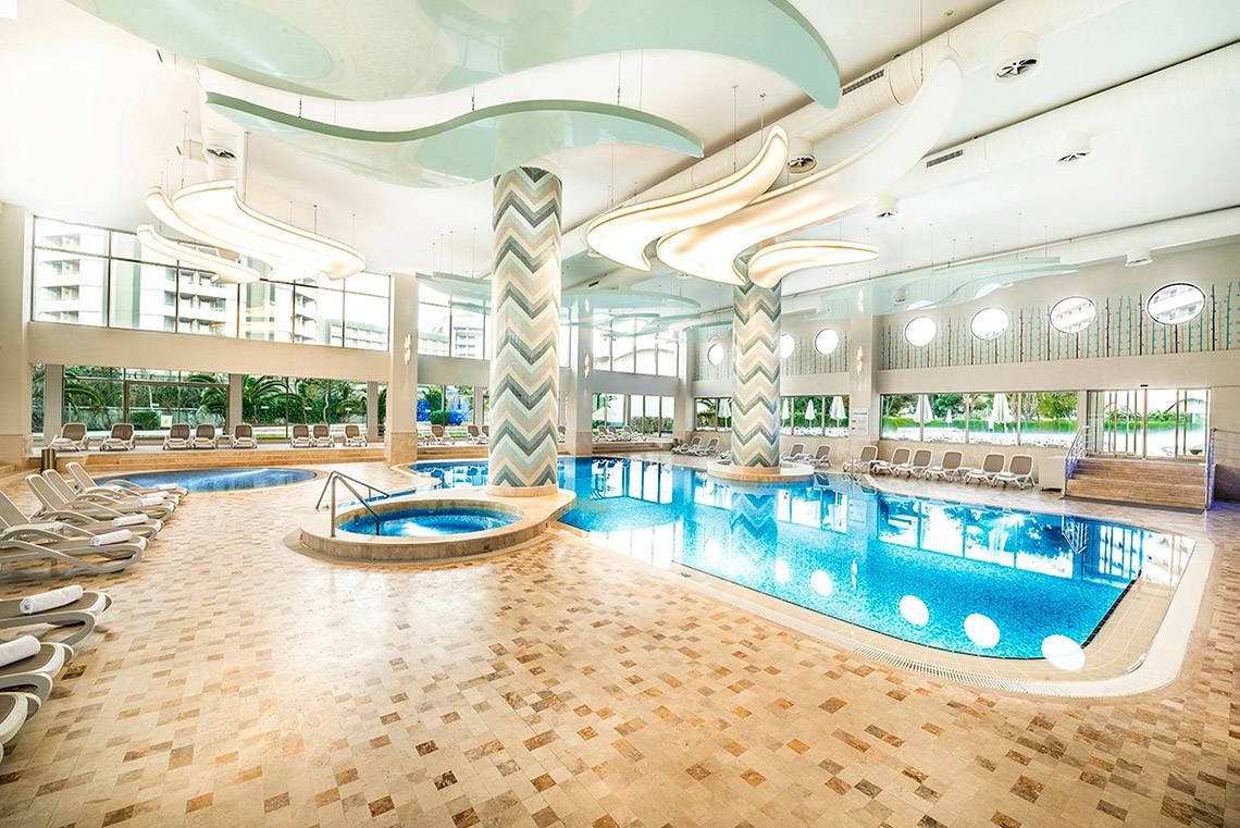 Innenpool des Titanic Deluxe Lara Hotels mit Loungebereich und geschwungenen Säulen