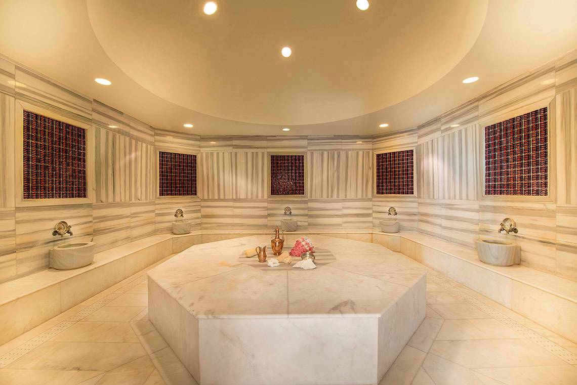 Innenbereich der Sauna im Titanic Deluxe Lara Hotel mit acht Sitzbänken und einem zentralen Tisch.