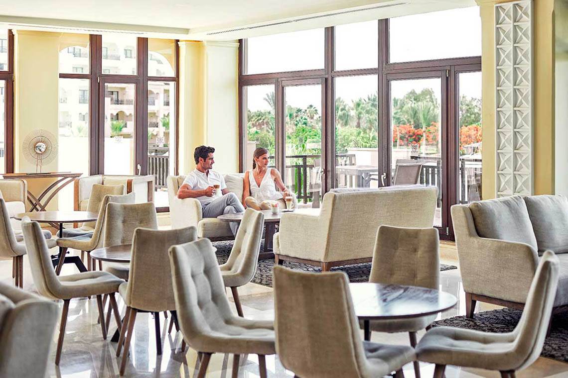 Ein Paar entspannt in der Lounge des Steigenberger ALDAU Beach Hotels mit Blick auf eine Terrasse.