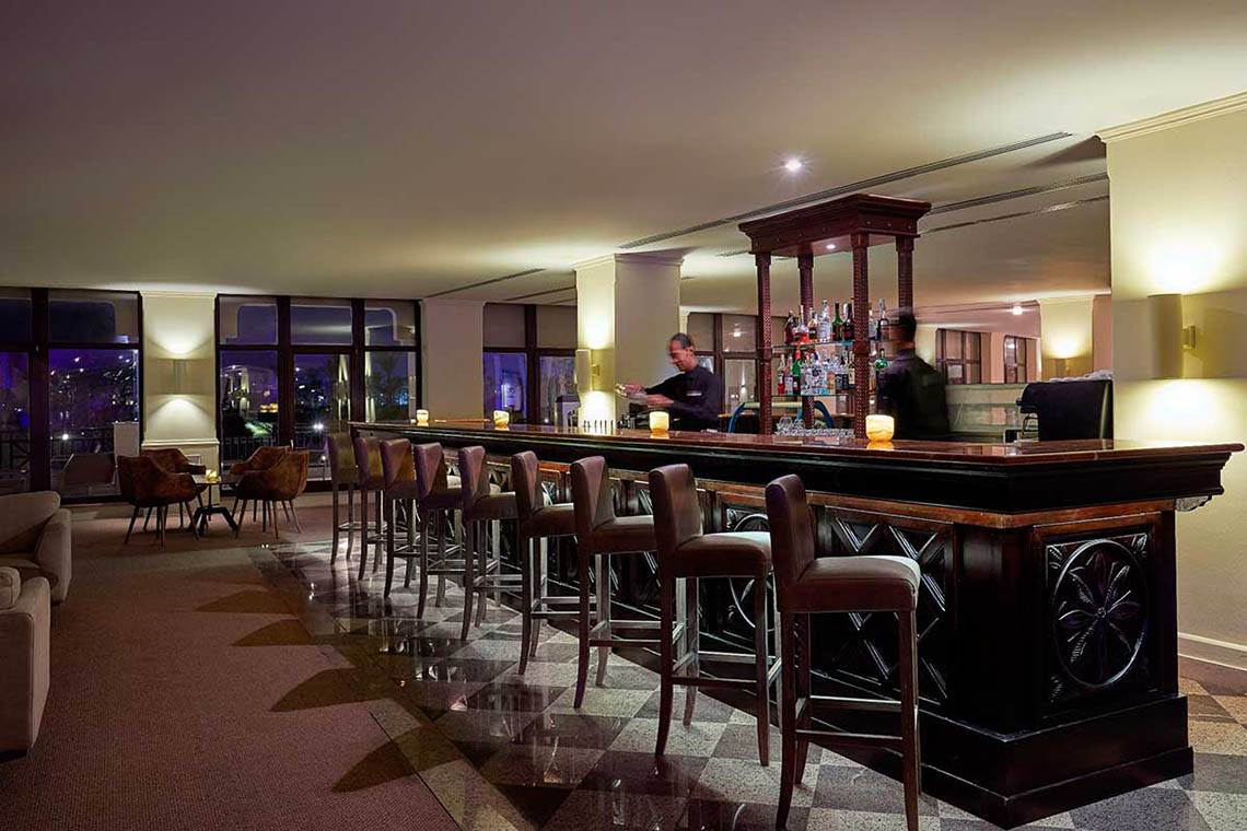 Innenansicht der Bar im Steigenberger ALDAU Beach Hotel mit Barkeepern und Gästen.