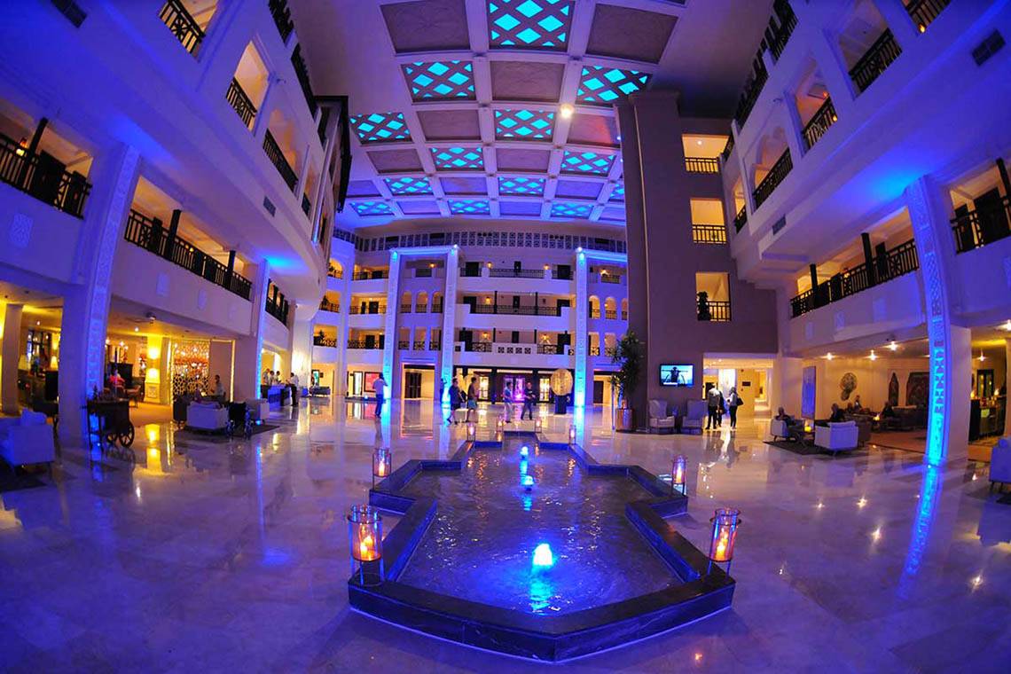 Lobby des Steigenberger ALDAU Beach Hotels mit Wasserbrunnen und blauer Beleuchtung.