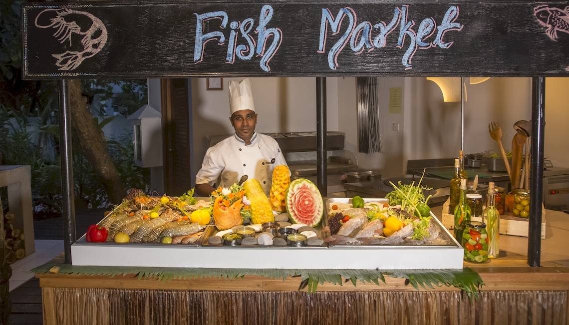 Ein Koch steht hinter einem Fischmarktstand im Reethi Beach Resort.