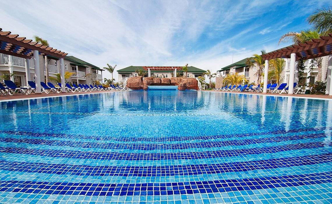 Schwimmbad des Valentin Varadero El Patriarca Hotels mit blauen Liegen und grünen Gebäuden