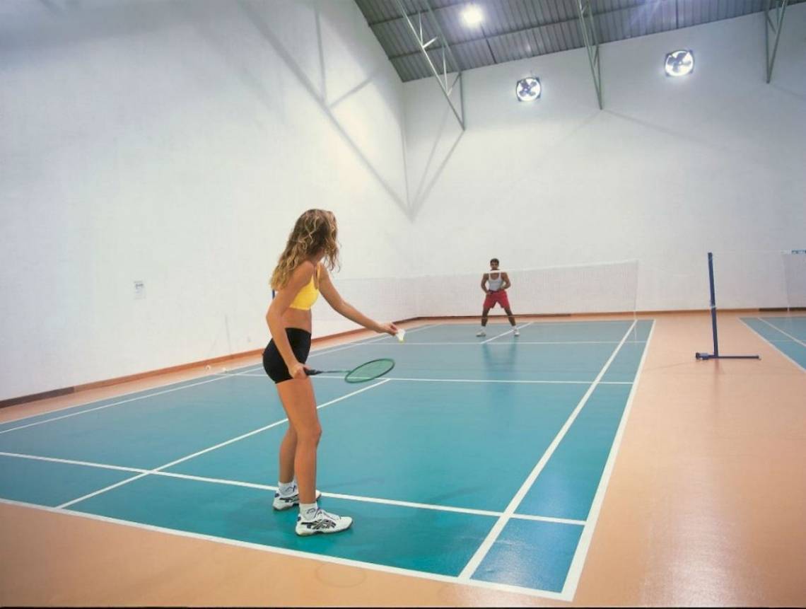 Im Reethi Beach Resort spielen zwei Personen Badminton auf einem Hallenplatz.